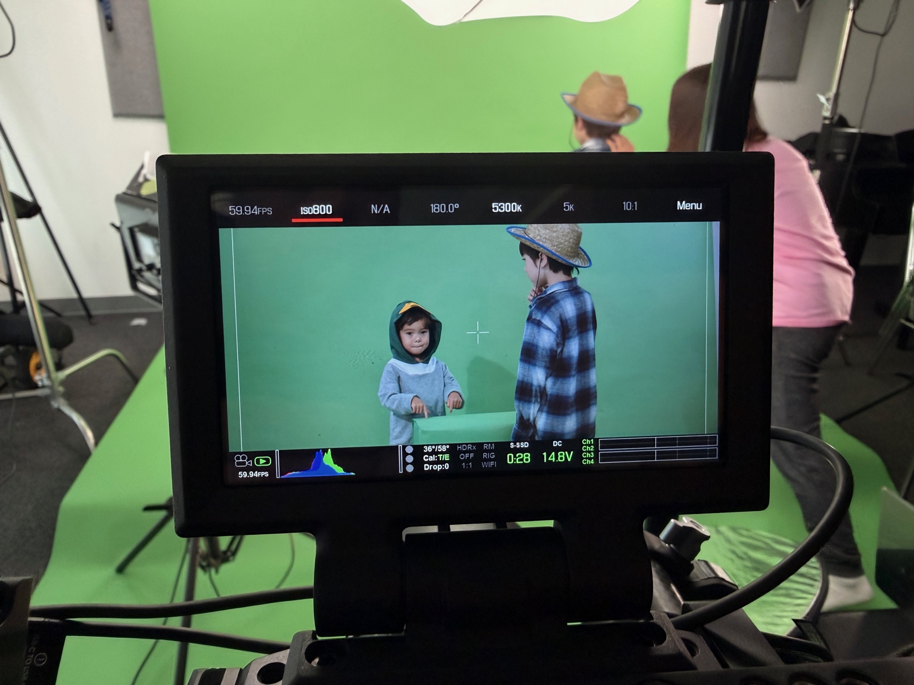 Behind the scenes: a production monitor framing a green-screen shoot